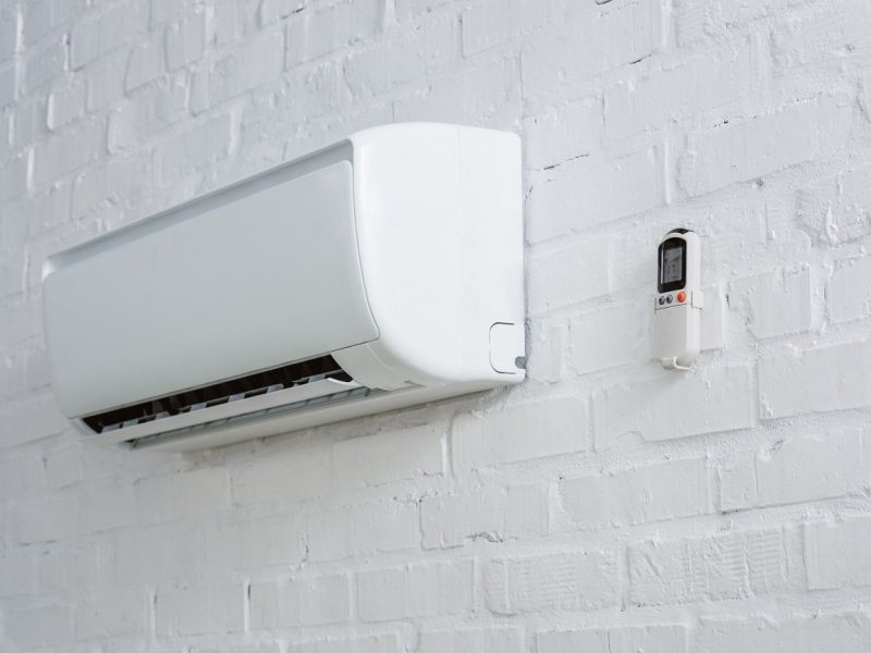 air conditioner hanging on white brick wall with remote control
