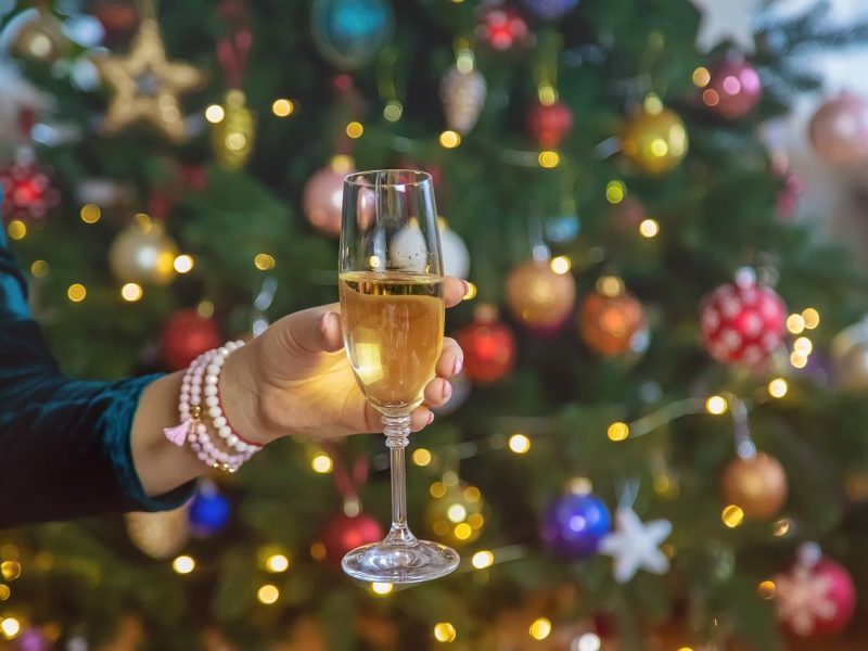Champagne in hand against the background of the Christmas tree. Selective focus.